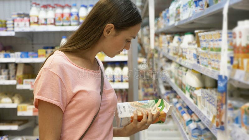 Γυναίκα που επιλέγει τα γαλακτοκομικά τρόφιμα στο ψυγείο στο τμήμα παντοπωλείων λεωφόρου αγορών στοκ εικόνες Γυναίκα που επιλέγει τα γαλακτοκομικά τρόφιμα στο ψυγείο στο τμήμα παντοπωλείων λεωφόρου αγορών στοκ εικόνες