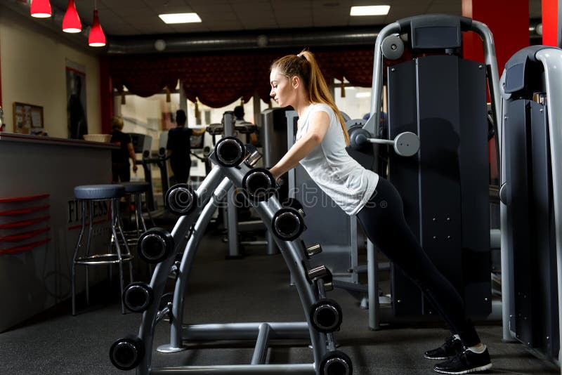 Γυναίκα που κλίνει σε μια στάση των barbells σε μια γυμναστική στοκ φωτογραφίες Γυναίκα που κλίνει σε μια στάση των barbells σε μια γυμναστική στοκ φωτογραφίες