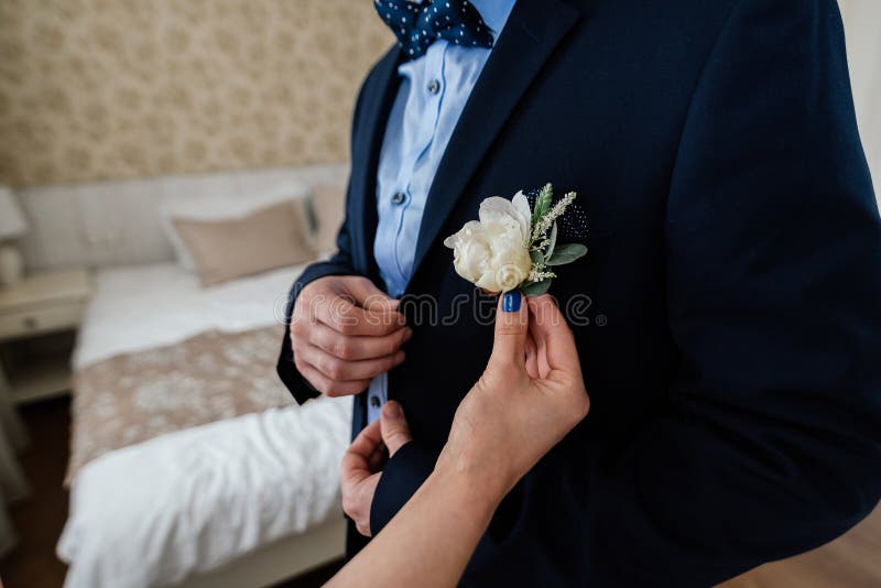 Γυναίκα που παρεμβάλλει τη μπουτονιέρα buttonhole του άνδρα στο κοστούμι στοκ εικόνα με δικαίωμα ελεύθερης χρήσης Γυναίκα που παρεμβάλλει τη μπουτονιέρα buttonhole του άνδρα στο κοστούμι στοκ εικόνα με δικαίωμα ελεύθερης χρήσης