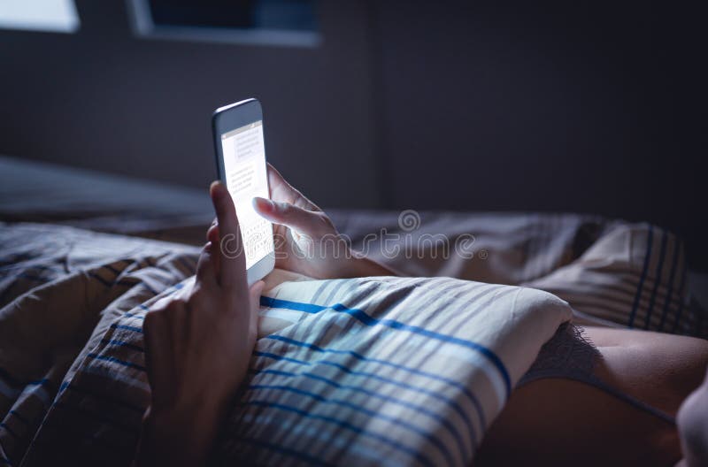 Woman using phone late at night in bed. Person looking at text messages with cell in dark home. Hipster online dating or texting with smartphone. Sexting or cheating concept. Smart device screen light. Woman using phone late at night in bed. Person looking at text messages with cell in dark home. Hipster online dating or texting with smartphone. Sexting or cheating concept. Smart device screen light