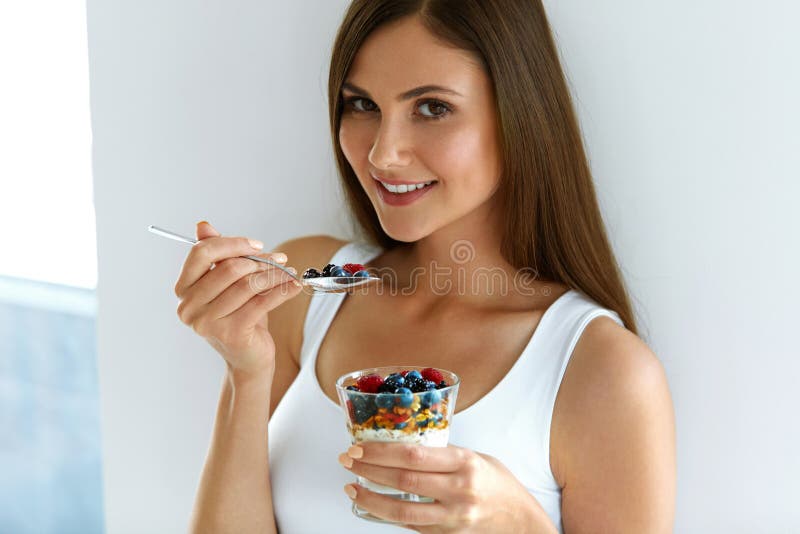 Γυναίκα που τρώει το γιαούρτι, τα μούρα και Oatmeal για το υγιές πρόγευμα στοκ εικόνες Γυναίκα που τρώει το γιαούρτι, τα μούρα και Oatmeal για το υγιές πρόγευμα στοκ εικόνες