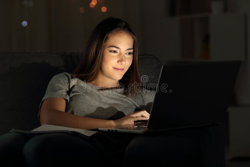Γυναίκα που χρησιμοποιεί ένα lap-top στη νύχτα σε έναν καναπέ στοκ εικόνα