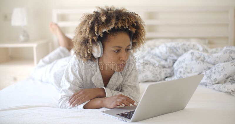 Γυναίκα που χρησιμοποιεί το lap-top της στο κρεβάτι στοκ εικόνες με δικαίωμα ελεύθερης χρήσης Γυναίκα που χρησιμοποιεί το lap-top της στο κρεβάτι στοκ εικόνες με δικαίωμα ελεύθερης χρήσης