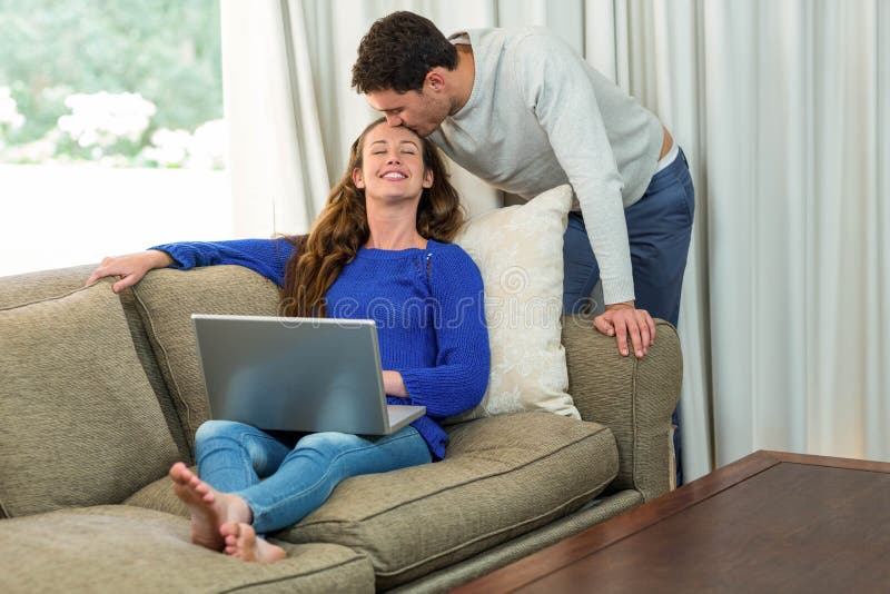 Γυναίκα που χρησιμοποιεί το φίλημα lap-top και ανδρών στο μέτωπό της στοκ φωτογραφία με δικαίωμα ελεύθερης χρήσης Γυναίκα που χρησιμοποιεί το φίλημα lap-top και ανδρών στο μέτωπό της στοκ φωτογραφία με δικαίωμα ελεύθερης χρήσης