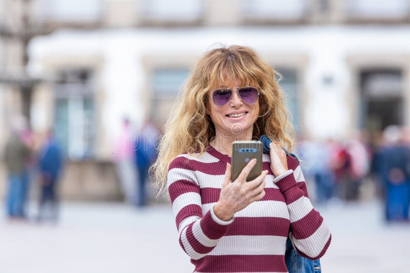 γυναίκα στο δρόμο κοιτάζει το κινητό ή το smartphone στοκ εικόνες