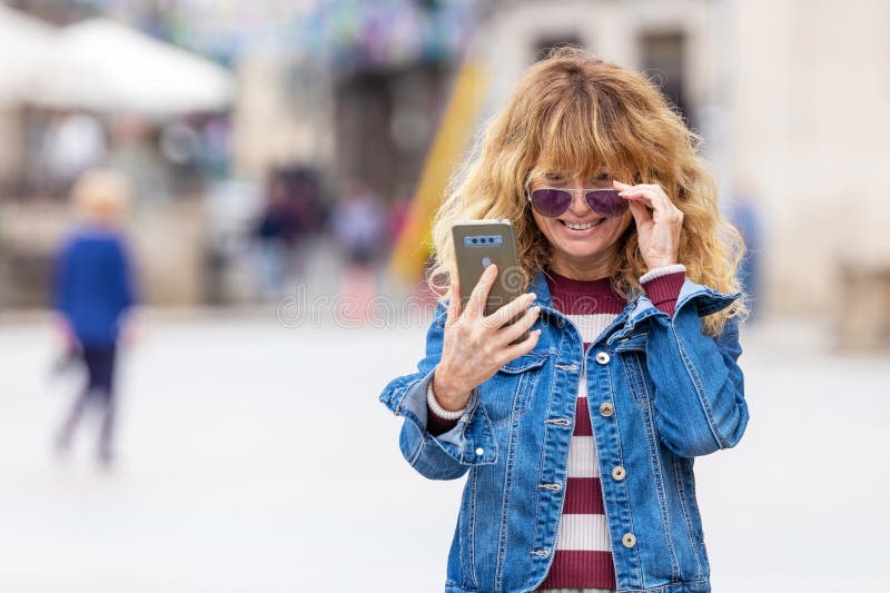 γυναίκα στο δρόμο κοιτάζει το κινητό ή το smartphone στοκ φωτογραφία με δικαίωμα ελεύθερης χρήσης