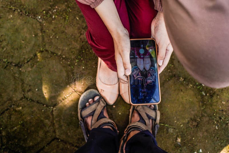 top view of a woman taking a photo of her partner's feet using a cellphone. top view of a woman taking a photo of her partner's feet using a cellphone.