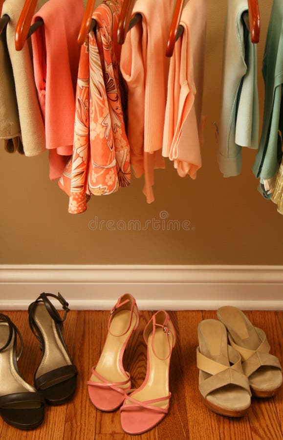 Ladies pastel spring clothing hanging on matching wooden hangers in closet. Ladies pastel spring clothing hanging on matching wooden hangers in closet