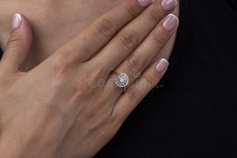 Solitaire marriage proposal ring on woman's finger while hand's on chest, wearing black shirt. Solitaire marriage proposal ring on woman's finger while hand's on chest, wearing black shirt.