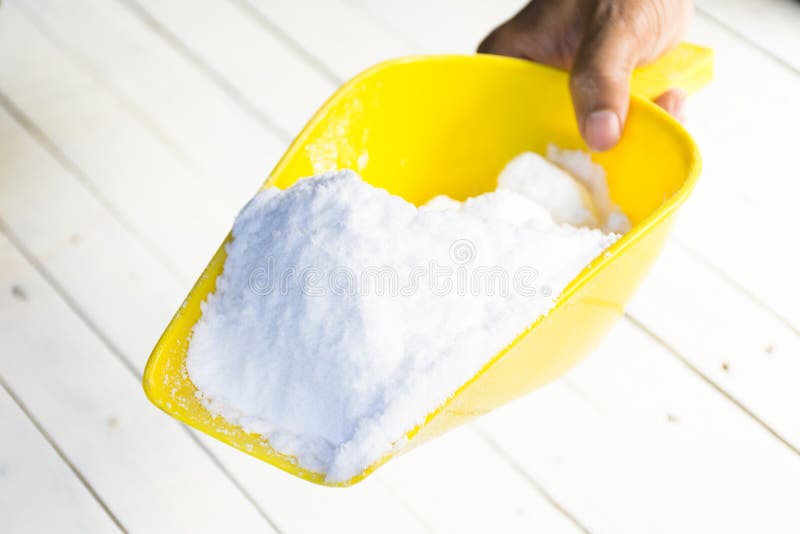 Dextrose in yellow shovel in hand on wooden white table.1. Dextrose in yellow shovel in hand on wooden white table.1