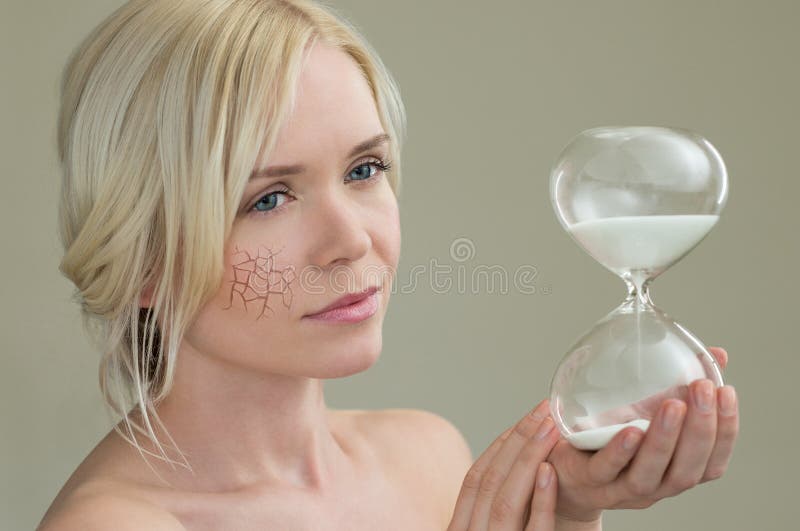 Beauty portrait of young woman holding hour glass sand timer, aging process concept. Beauty portrait of young woman holding hour glass sand timer, aging process concept
