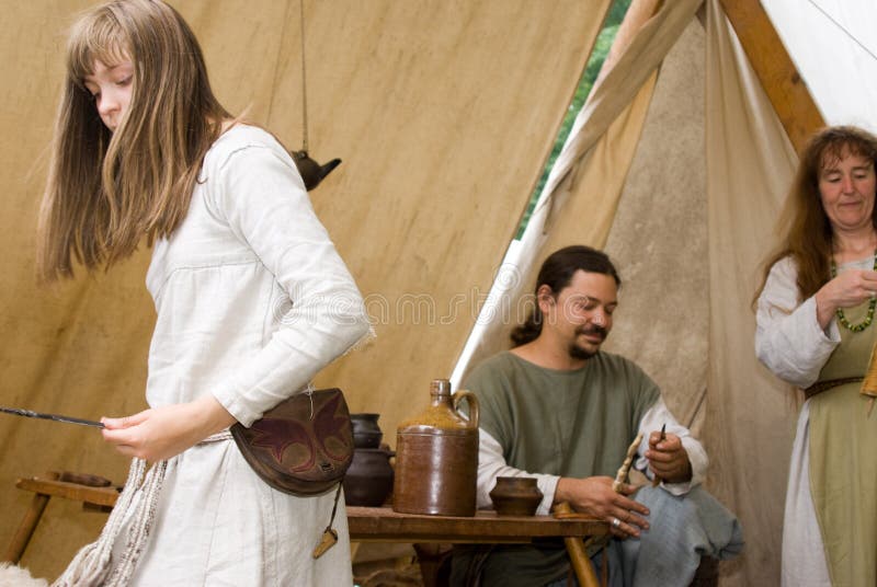 Farmer in middle ages with his wife and daughter during a camp. wife is making yarn by hand. Farmer in middle ages with his wife and daughter during a camp. wife is making yarn by hand