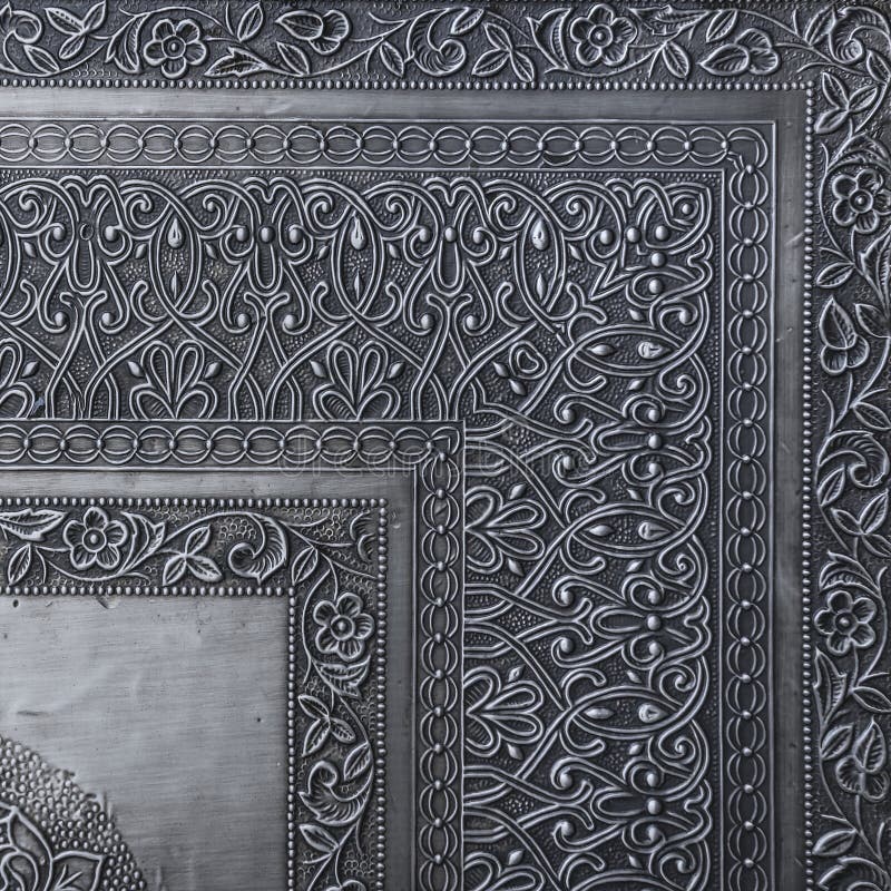 Decorative asian chasing art framework with arabesque pattern in form of embossing on metal.Textured metal frame backdrop with ancient oriental floral wavy ornament. Carved silver black background. Decorative asian chasing art framework with arabesque pattern in form of embossing on metal.Textured metal frame backdrop with ancient oriental floral wavy ornament. Carved silver black background.