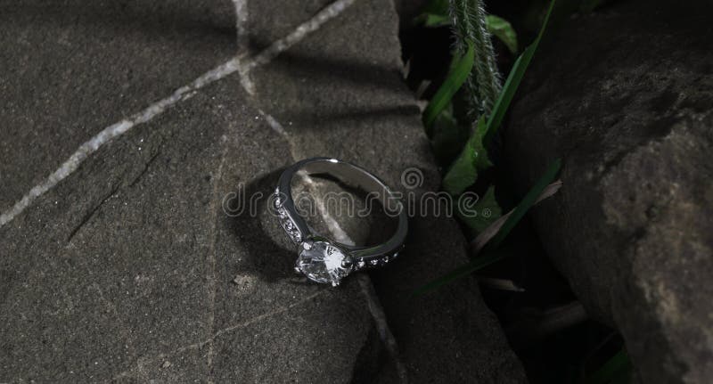 Diamond Solitaire Ring on a rock between grass with copy space. Diamond Solitaire Ring on a rock between grass with copy space