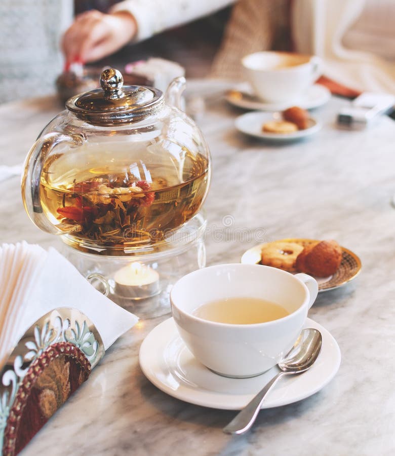 Διαφανές teapot γυαλιού με το πράσινο τσάι σε έναν πίνακα σε έναν καφέ, εκλεκτική εστίαση στοκ φωτογραφία Διαφανές teapot γυαλιού με το πράσινο τσάι σε έναν πίνακα σε έναν καφέ, εκλεκτική εστίαση στοκ φωτογραφία