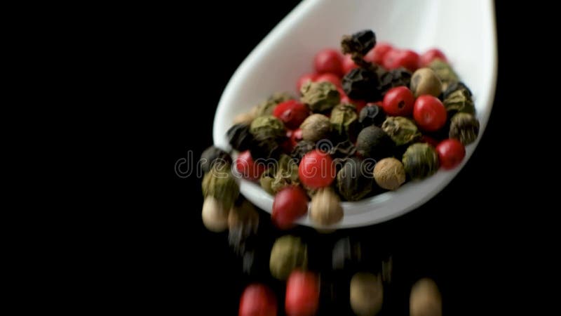 διαφορετικοί τύποι peppercorns που τροφοδοτούν το μαύρο φόντο βραδείας κίνησης. κόκκινο πράσινο λευκό και μαύρο πιπέρι. φιλμ μικρού μήκους