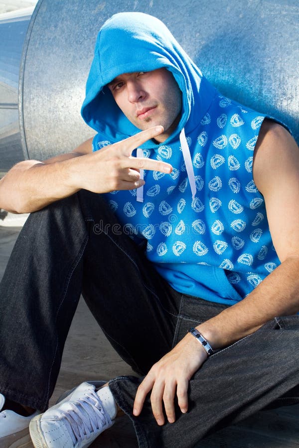 A cool hip hop dude posing in hip hop style clothing and giving peace sign. A cool hip hop dude posing in hip hop style clothing and giving peace sign