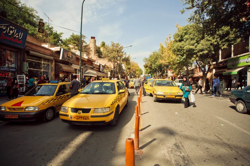 SANANDAJ, IRAN: People walking on street road with line of taxi cars of yellow color. Capital of Kurdish culture & Kurdistan Province, Sanandaj has population of 380,000. SANANDAJ, IRAN: People walking on street road with line of taxi cars of yellow color. Capital of Kurdish culture & Kurdistan Province, Sanandaj has population of 380,000