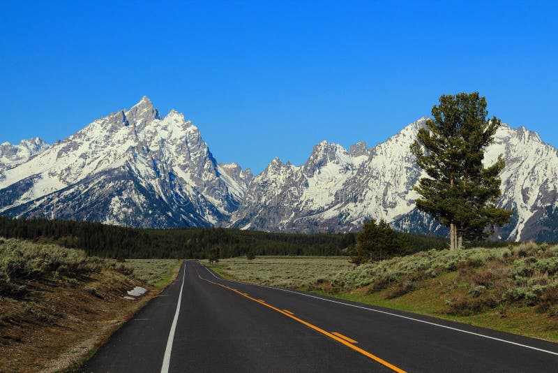 Δρόμος στα δύσκολα βουνά εθνικό πάρκο Teton πρωινού στο ελαφρύ, μεγάλο, Ουαϊόμινγκ στοκ φωτογραφία Δρόμος στα δύσκολα βουνά εθνικό πάρκο Teton πρωινού στο ελαφρύ, μεγάλο, Ουαϊόμινγκ στοκ φωτογραφία