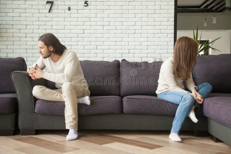 Δυστυχισμένη λυπημένη συνεδρίαση ζευγών στον καναπέ μετά από τη φιλονικία στο σπίτι στοκ φωτογραφία Δυστυχισμένη λυπημένη συνεδρίαση ζευγών στον καναπέ μετά από τη φιλονικία στο σπίτι στοκ φωτογραφία