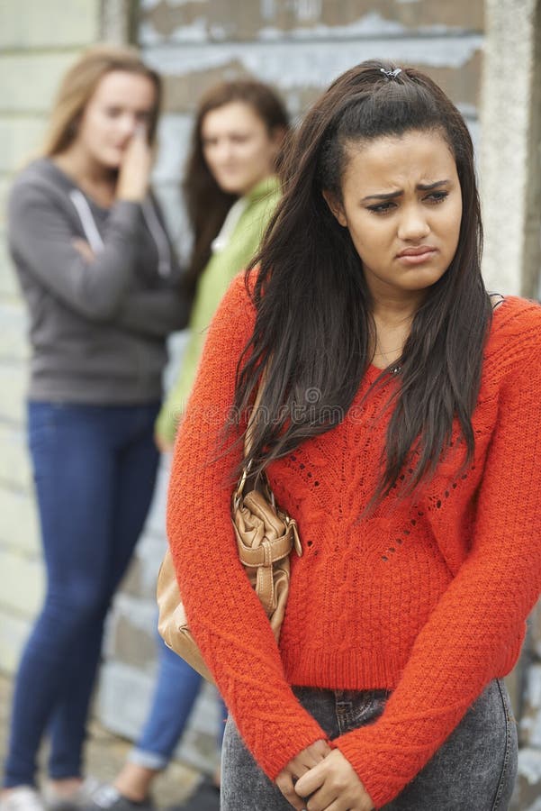 Unhappy Teenage Girl Being Gossiped About By Peers Outdoors. Unhappy Teenage Girl Being Gossiped About By Peers Outdoors