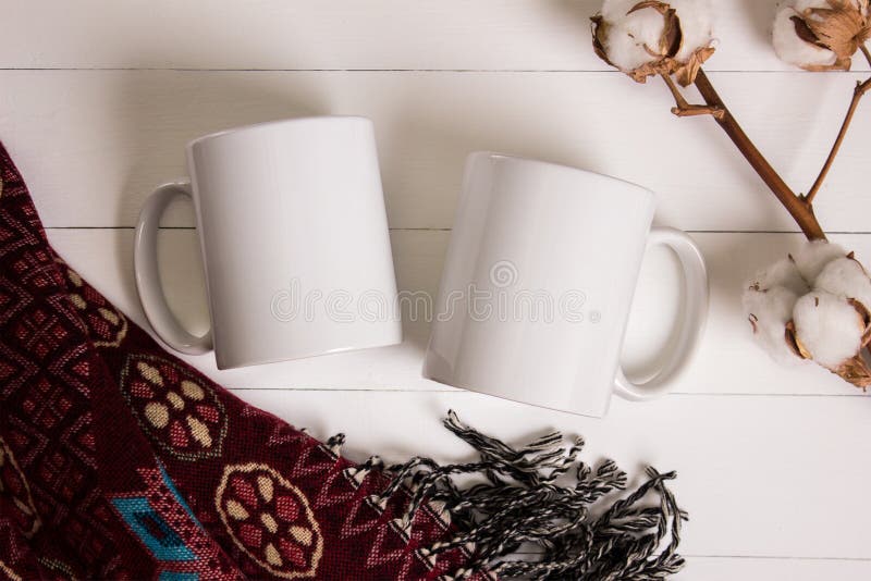 Two white mugs, pair of cups, Mockup. Cozy atmosphere, wooden background, cotton and wool decorations for winter gifts. Two white mugs, pair of cups, Mockup. Cozy atmosphere, wooden background, cotton and wool decorations for winter gifts.