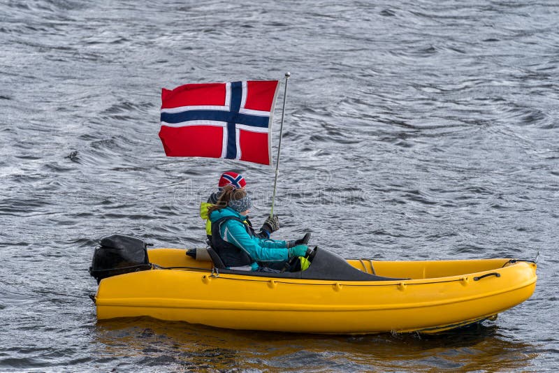 ULSTEINVIK, NORWAY - 2020 MAY 17. Two person on a small yellow boat celebrate the national day in Norway during covid19. ULSTEINVIK, NORWAY - 2020 MAY 17. Two person on a small yellow boat celebrate the national day in Norway during covid19