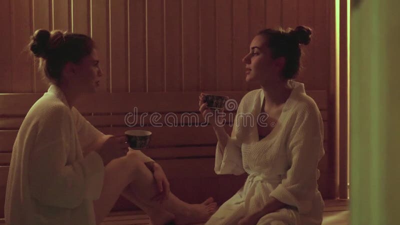 Δύο γυναίκες πίνουν το βοτανικό τσάι στη spa κεντρική SPA που δεν θα έχουν την αφυδάτωση