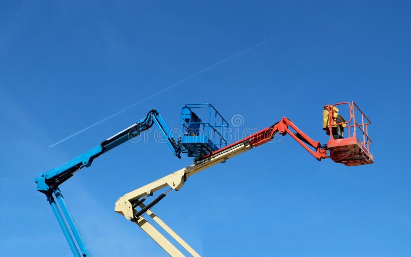 Red white and blue aerial work platforms of cherry picker against blue sky. Red white and blue aerial work platforms of cherry picker against blue sky