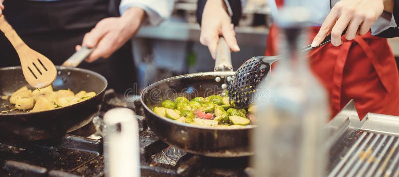 δύο επιμελείς σεφ που εργάζονται σε μια ζεστή κουζίνα μαγειρεύουν νόστιμο φαγητό στοκ φωτογραφία με δικαίωμα ελεύθερης χρήσης