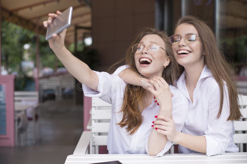 Δύο ευτυχή κορίτσια που κάνουν ένα selfie στο θερινό καφέ στοκ φωτογραφία με δικαίωμα ελεύθερης χρήσης Δύο ευτυχή κορίτσια που κάνουν ένα selfie στο θερινό καφέ στοκ φωτογραφία με δικαίωμα ελεύθερης χρήσης