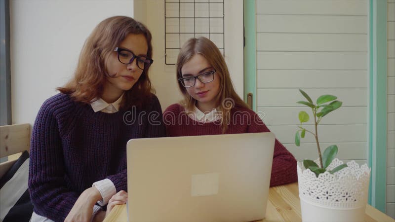 Δύο κορίτσια που μιλούν στους φίλους μέσω του webchat ή που έχουν μια τηλεοπτική συνομιλία στον καφέ