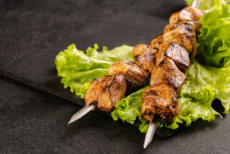 δύο μερίδες shish kebab σε ένα πέτρινο πιάτο με σαλάτα.