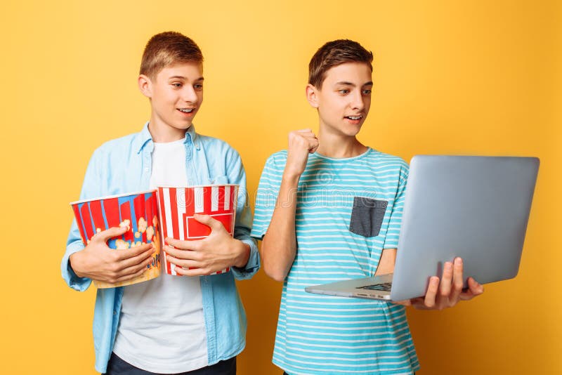 Δύο φίλοι εφήβων με έναν κάδο popcorn στα χέρια τους και ενός lap-top που προετοιμάζεται να προσέξει τους κινηματογράφους σε ένα στοκ εικόνες Δύο φίλοι εφήβων με έναν κάδο popcorn στα χέρια τους και ενός lap-top που προετοιμάζεται να προσέξει τους κινηματογράφους σε ένα στοκ εικόνες