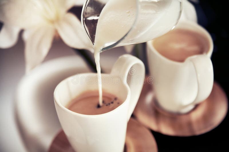 Two white cups of coffee with decoration and poured milk. Two white cups of coffee with decoration and poured milk