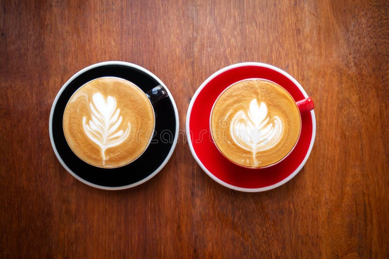 Δύο φλυτζάνια του καυτού καφέ με την τέχνη latte στον ξύλινο πίνακα Αγαπημένο ποτό του ποτού caffein στοκ εικόνα Δύο φλυτζάνια του καυτού καφέ με την τέχνη latte στον ξύλινο πίνακα Αγαπημένο ποτό του ποτού caffein στοκ εικόνα