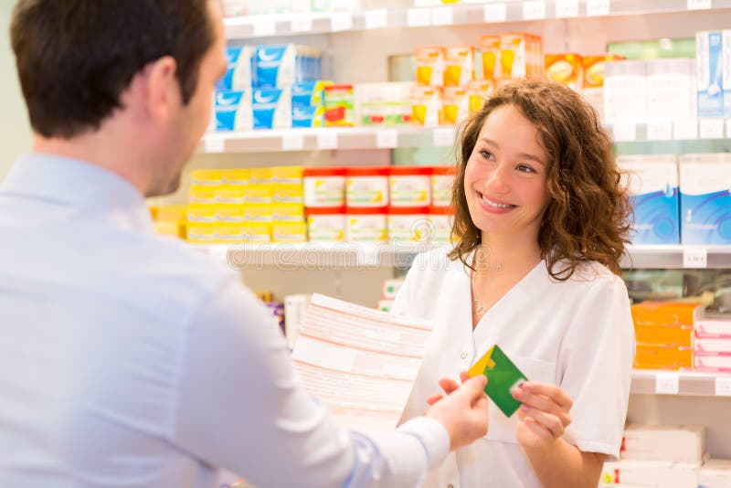 Ελκυστικός φαρμακοποιός που παίρνει healt την ασφαλιστική κάρτα στοκ φωτογραφία με δικαίωμα ελεύθερης χρήσης Ελκυστικός φαρμακοποιός που παίρνει healt την ασφαλιστική κάρτα στοκ φωτογραφία με δικαίωμα ελεύθερης χρήσης