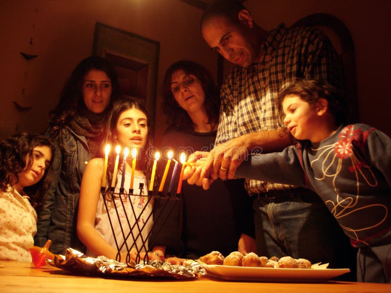 A family is lighting a candle for the Jewish holiday of Hanukkah. A family is lighting a candle for the Jewish holiday of Hanukkah.