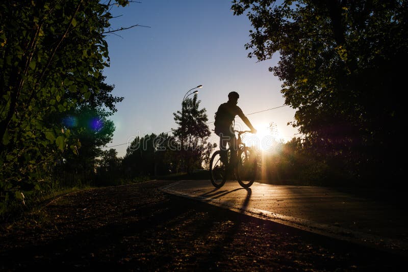 Εικόνα του bicyclist που φορά την οδήγηση κρανών γύρω από την πόλη το βράδυ στοκ φωτογραφία Εικόνα του bicyclist που φορά την οδήγηση κρανών γύρω από την πόλη το βράδυ στοκ φωτογραφία