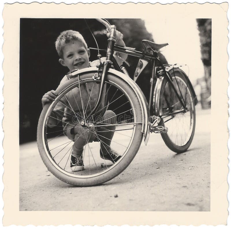 Vintage Snapshot of a cute little boy, kneeling behind his shiny new-looking 1940s-50s bicycle. Vintage Snapshot of a cute little boy, kneeling behind his shiny new-looking 1940s-50s bicycle.