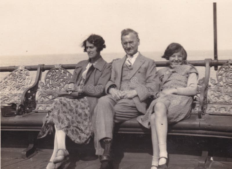 Vintage black and white photo of man, women and young girl at the seaside on family holiday, 1950s. Social History, 1950s fashion, family holiday in the 1950s. Vintage black and white photo of man, women and young girl at the seaside on family holiday, 1950s. Social History, 1950s fashion, family holiday in the 1950s.