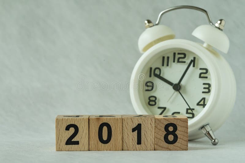 Εκλεκτική εστίαση στον ξύλινο φραγμό 2018 κύβων με το άσπρο ξυπνητήρι στοκ εικόνες Εκλεκτική εστίαση στον ξύλινο φραγμό 2018 κύβων με το άσπρο ξυπνητήρι στοκ εικόνες