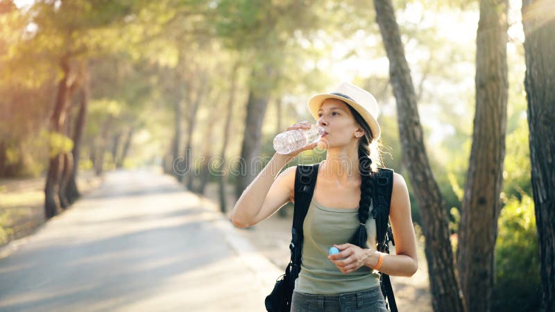 Ελκυστική νέα αναζωογόνηση κοριτσιών τουριστών από το πόσιμο νερό μετά από το ταξίδι backpacker στοκ εικόνες Ελκυστική νέα αναζωογόνηση κοριτσιών τουριστών από το πόσιμο νερό μετά από το ταξίδι backpacker στοκ εικόνες