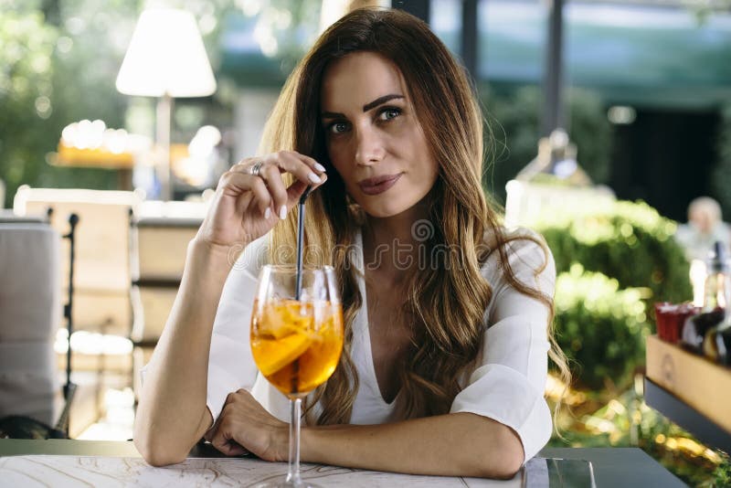 Ελκυστική νέα γυναίκα που πίνει coctail στον καφέ υπαίθριο στοκ φωτογραφία με δικαίωμα ελεύθερης χρήσης Ελκυστική νέα γυναίκα που πίνει coctail στον καφέ υπαίθριο στοκ φωτογραφία με δικαίωμα ελεύθερης χρήσης