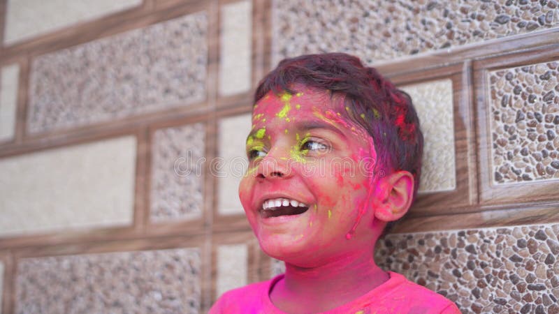 Cute little boy posing with exploding pink and green Holi powder around his. Cute little boy posing with exploding pink and green Holi powder around his
