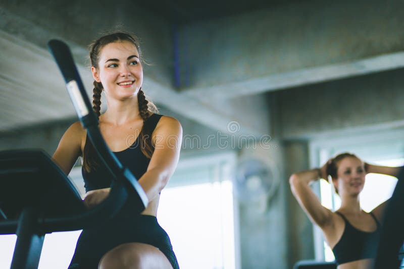 Ελκυστικό γυναικών στη γυμναστική, που ασκεί τα πόδια που κάνουν τα καρδιο ποδήλατα ανακύκλωσης workout Λέσχη ικανότητας με τα πο
