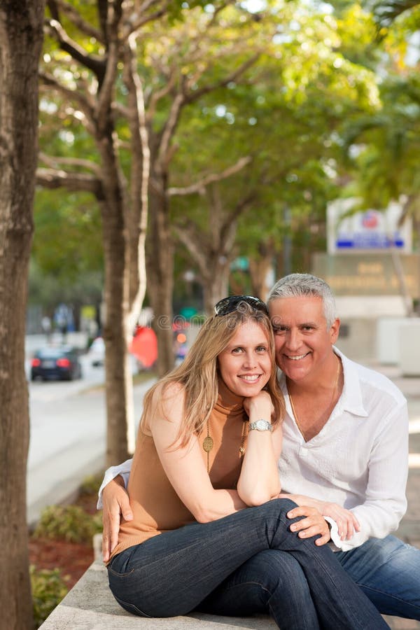 Attractive middle age couple posing along Miami's Brickell Avenue in the late afternoon with trees and street in the background. Attractive middle age couple posing along Miami's Brickell Avenue in the late afternoon with trees and street in the background.