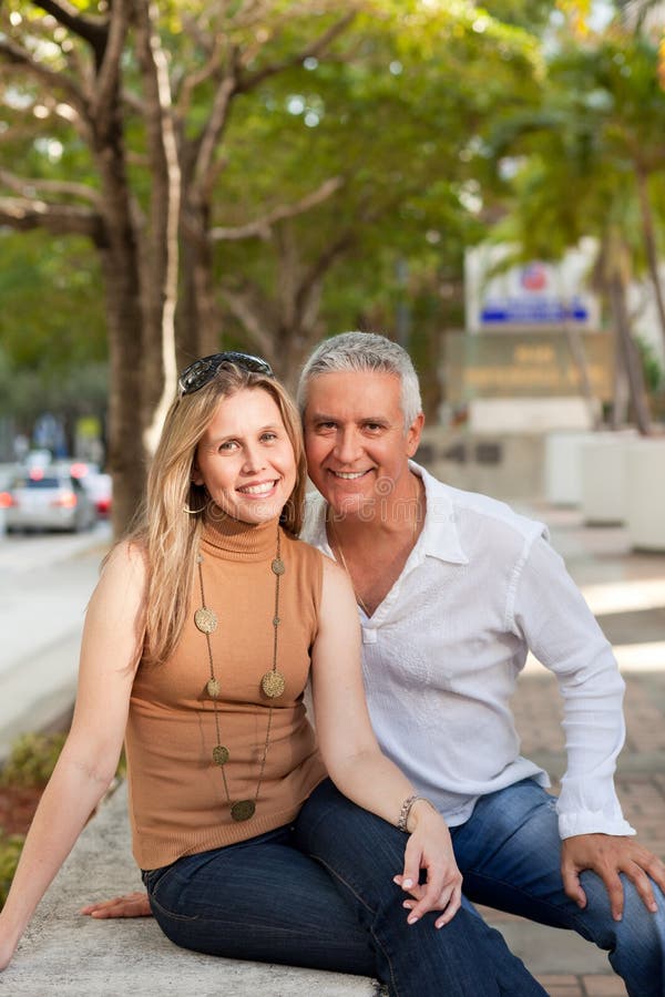 Attractive middle age couple posing along Miami's Brickell Avenue in the late afternoon with trees and street in the background. Attractive middle age couple posing along Miami's Brickell Avenue in the late afternoon with trees and street in the background.