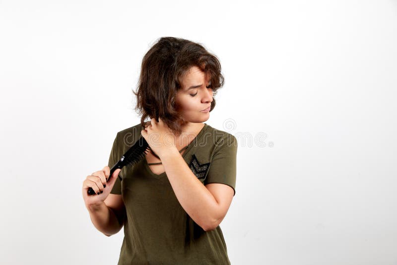 Ελκυστικό νέο θηλυκό brunette στο περιστασιακό χακί πουκάμισο που βουρτσίζει με τη σκοτεινή σγουρή τρίχα χτενών στοκ φωτογραφία Ελκυστικό νέο θηλυκό brunette στο περιστασιακό χακί πουκάμισο που βουρτσίζει με τη σκοτεινή σγουρή τρίχα χτενών στοκ φωτογραφία