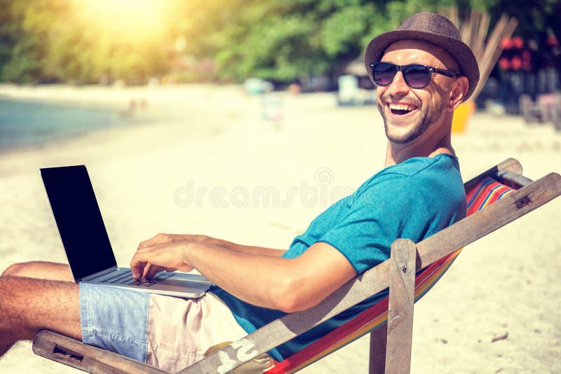 Ελκυστικός νεαρός άνδρας με το lap-top που λειτουργεί στην παραλία Ελευθερία, στοκ φωτογραφία με δικαίωμα ελεύθερης χρήσης Ελκυστικός νεαρός άνδρας με το lap-top που λειτουργεί στην παραλία Ελευθερία, στοκ φωτογραφία με δικαίωμα ελεύθερης χρήσης